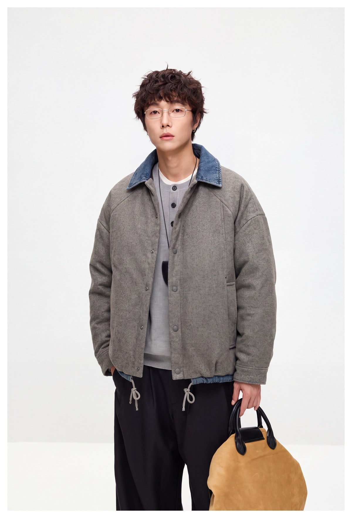 Close three-quarter view of model in gray jacket with denim collar, drawstring hem and snap front