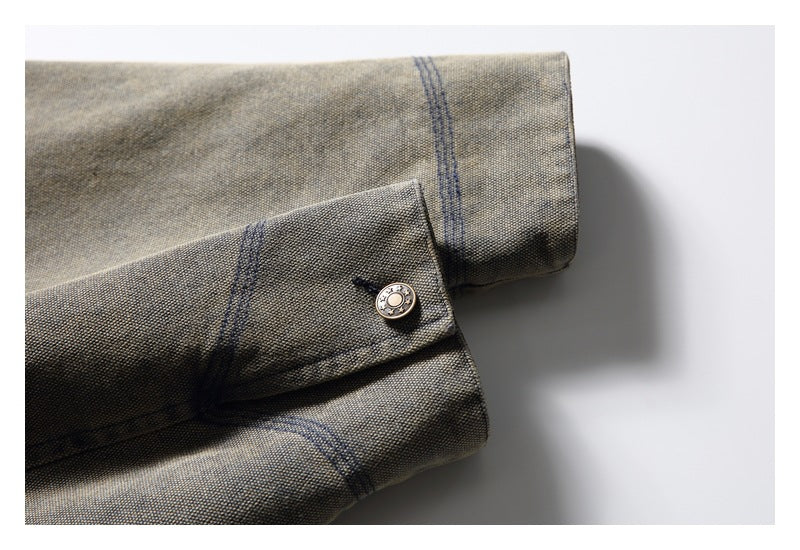 Close-up of a mottled gray-olive cuff with dark stitching and a round metal button.