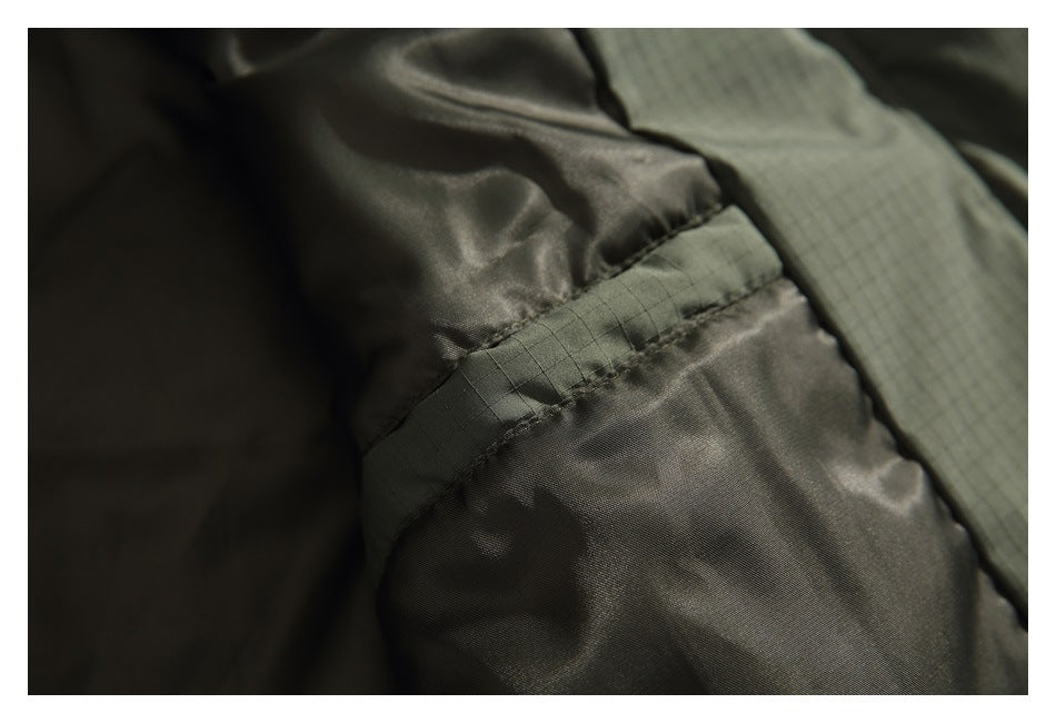 Close-up of a stitched seam joining the smooth dark lining to the olive grid-textured jacket shell.