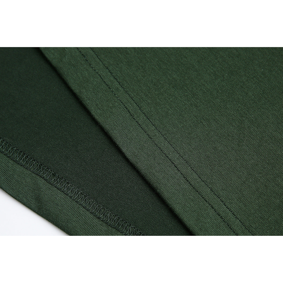 Close-up of stitching and hem finish on dark green polo fabric.