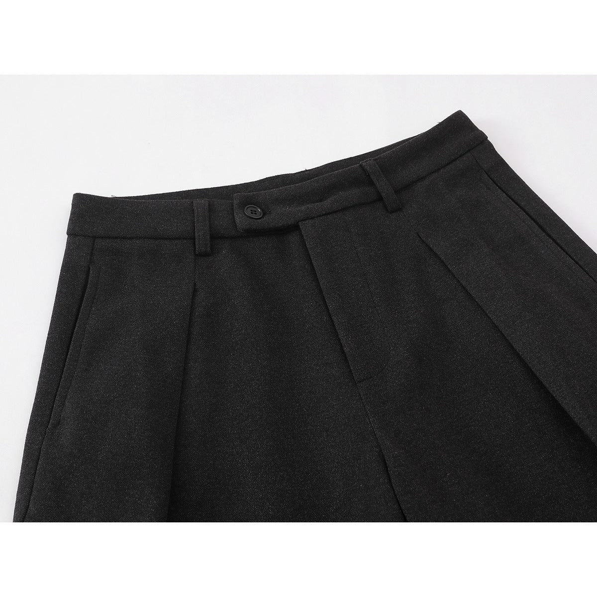 Close-up of charcoal trousers showing the buttoned waistband, belt loops, pleats, and front pocket opening.