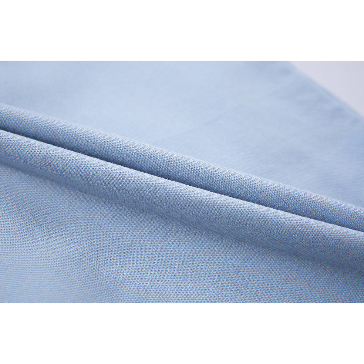 Macro view of light blue shirt fabric folded to show its fine woven surface.