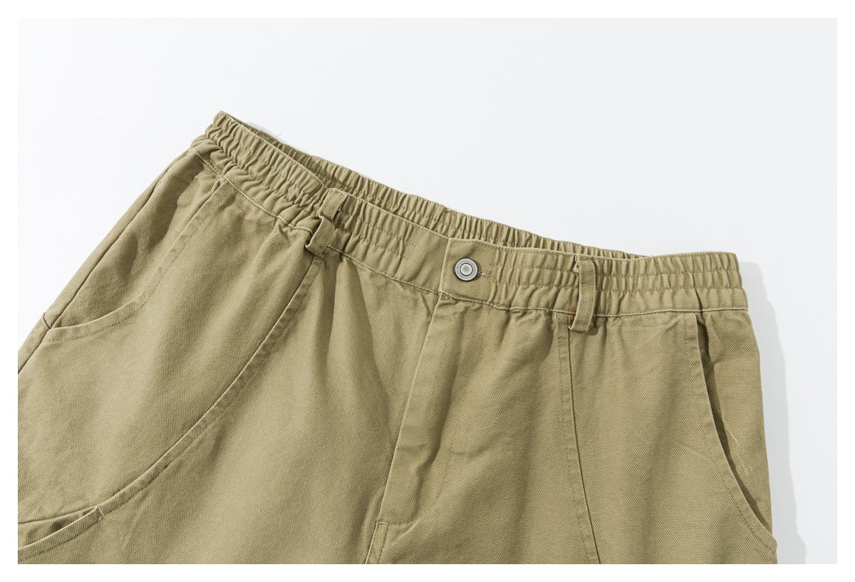 Close-up of the shorts’ elastic waistband, button closure, belt loops, and angled front pocket.