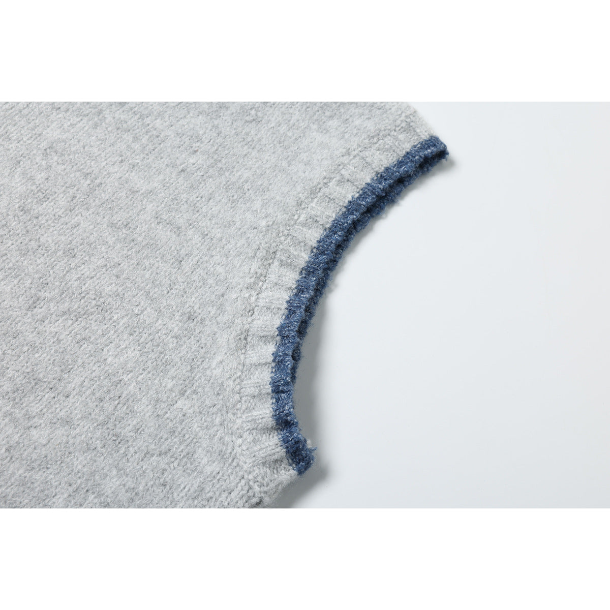 Close-up of a light gray knit top's curved armhole edge with dark blue trim.