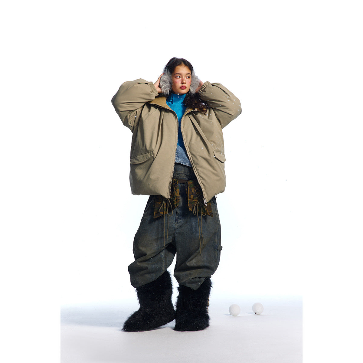 Model wearing an open taupe oversized jacket with a high collar and flap pockets, styled with dark baggy pants and black