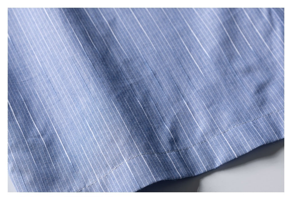 Close-up of the blue shirt's fine white stripes and stitched lower hem.