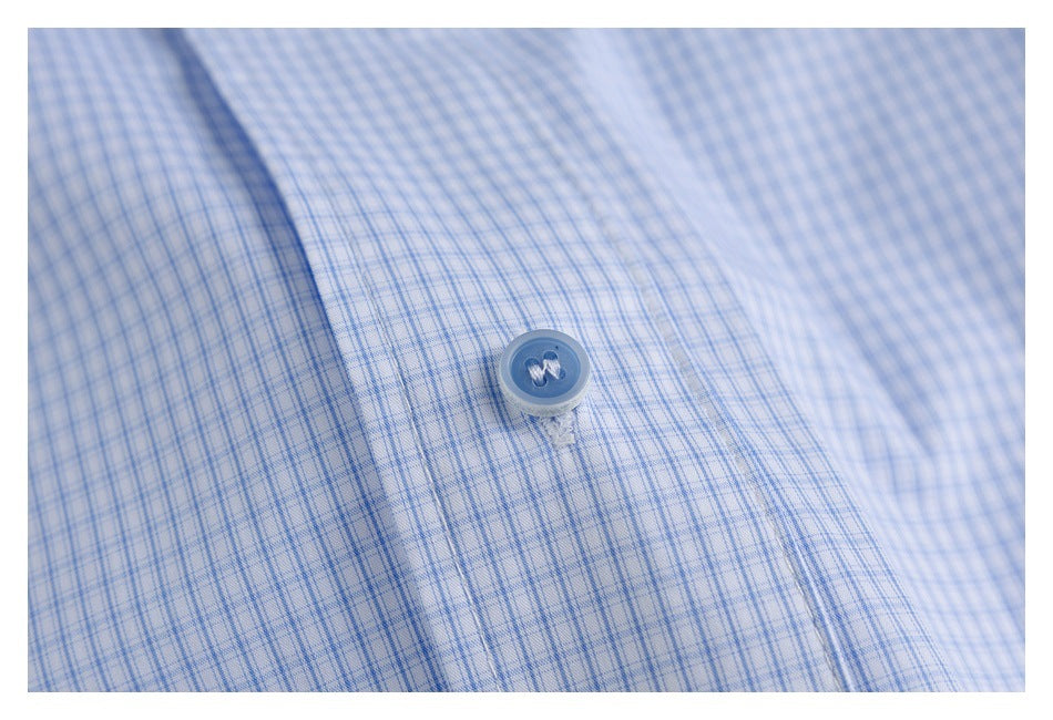Close-up of a light blue fine-check shirt fabric with a matching button.