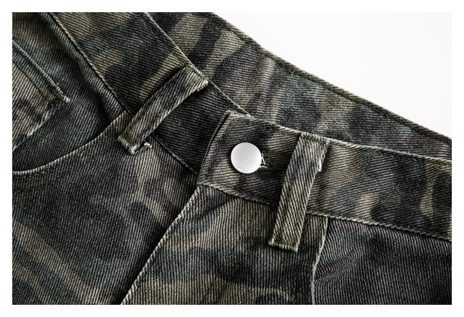 Close-up of the metal button, waistband, and belt loops on dark camouflage pants.