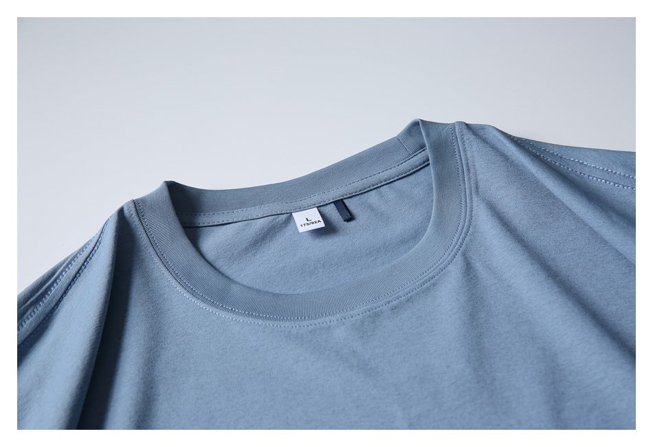 Close-up of the dusty blue T-shirt's crew neckline, shoulder seams, and small inner neck label.