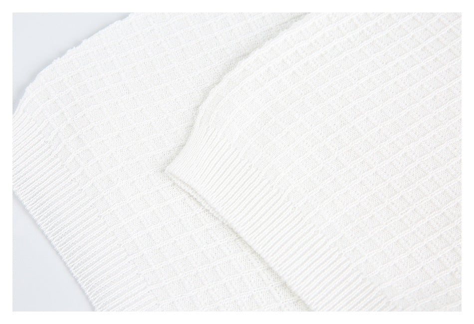Close-up of white knit with a ribbed cuff overlapping a textured sleeve panel.