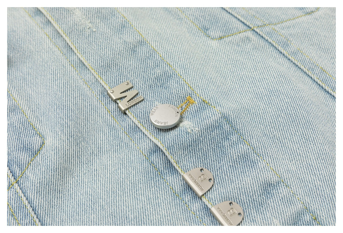 Close-up of silver-tone decorative hardware and yellow stitching on a pale blue denim jacket.