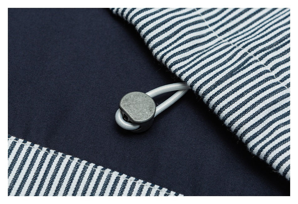 Close-up of a small metal button and loop fastening beside navy fabric and white-and-navy striped trim.