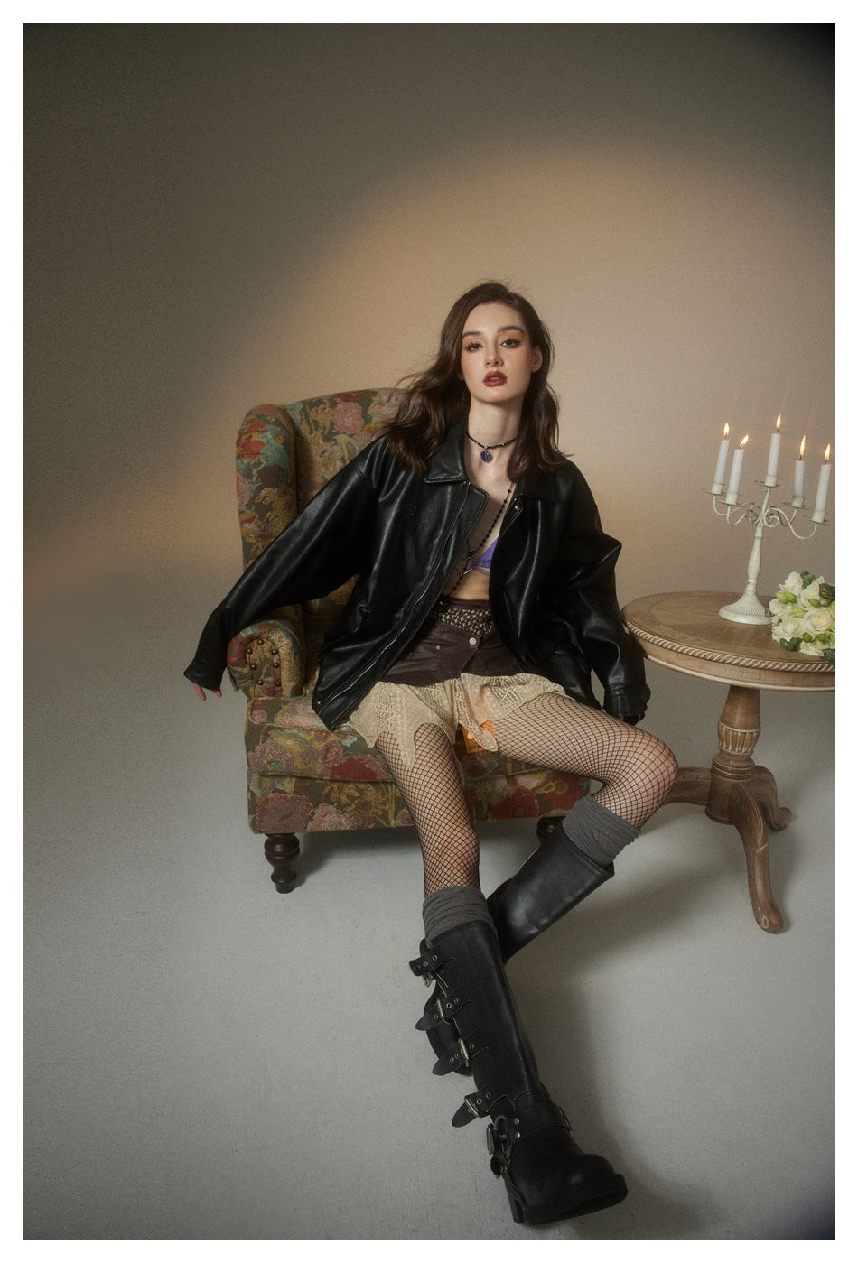 Seated model wearing an open black jacket with a wide collar and relaxed sleeves.