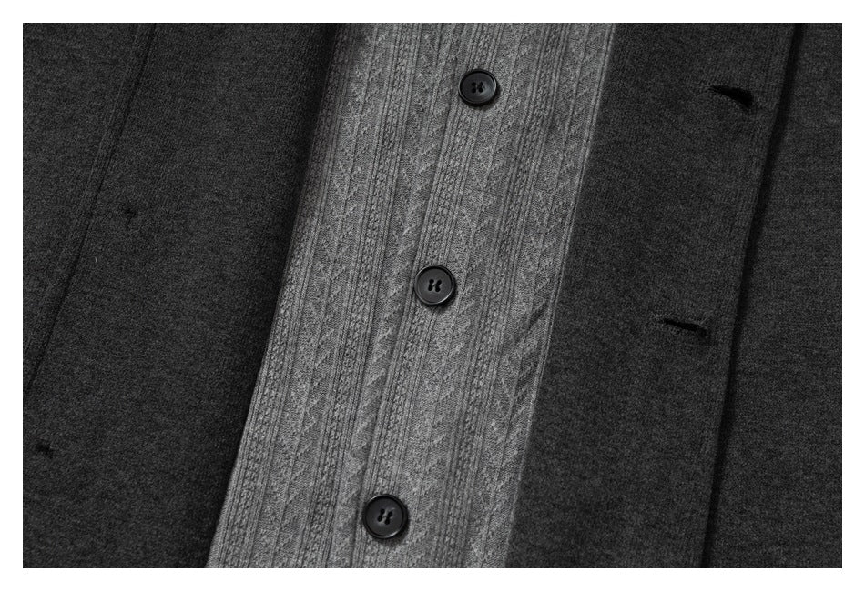 Close-up of a charcoal jacket front with black buttons, a gray cable-knit inset, and a welt pocket.