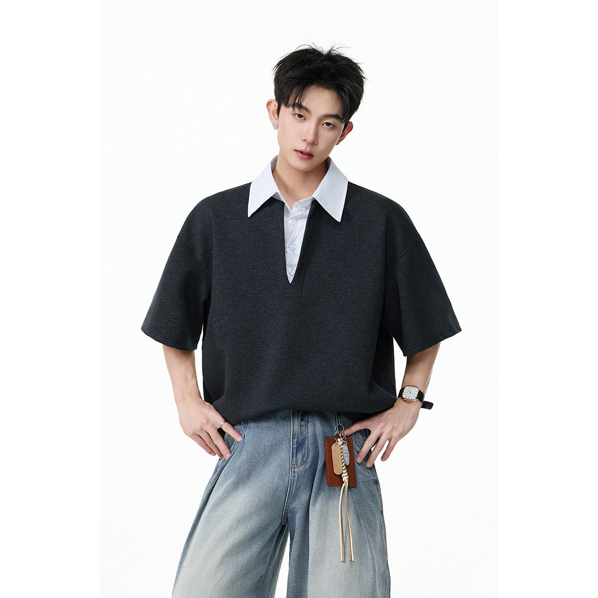 Close view of a model wearing a charcoal oversized short-sleeve shirt with a white pointed collar and button placket.