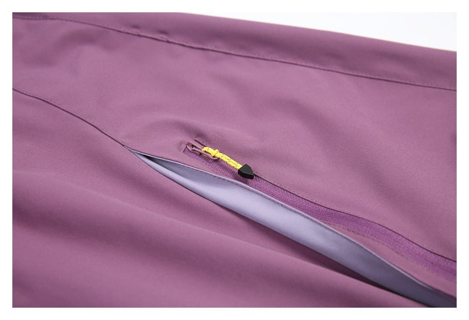 Close-up of purple trousers showing a diagonal zipper with a bright yellow pull and black tab.