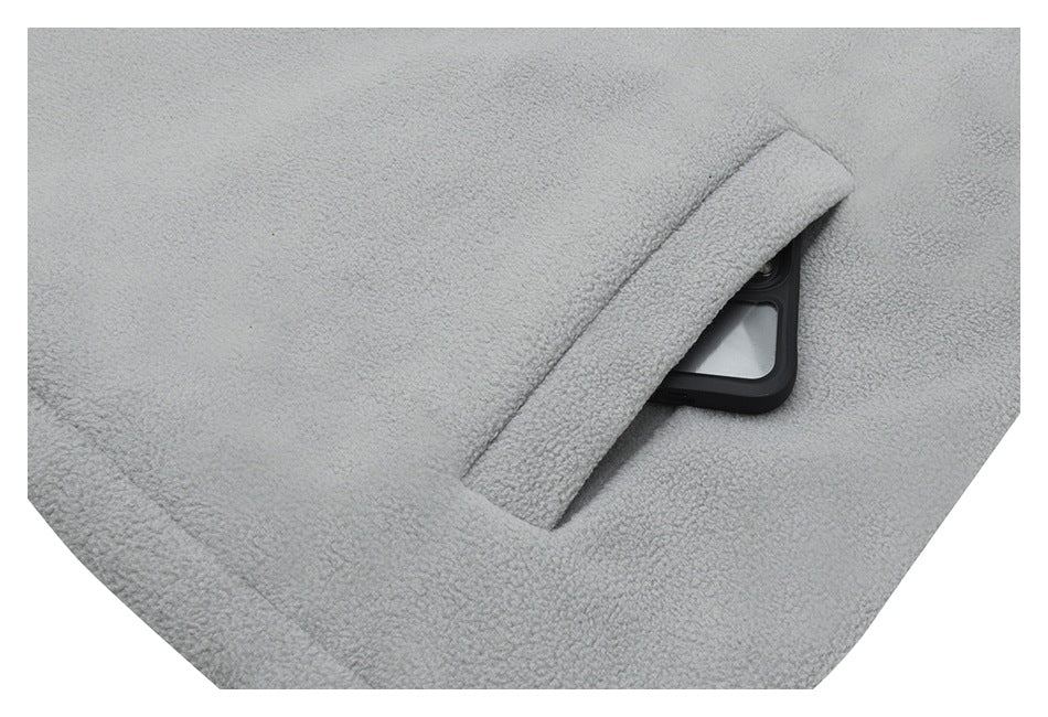 Close-up of a slit pocket on the light gray fleece jacket with a dark rectangular object partly visible inside.