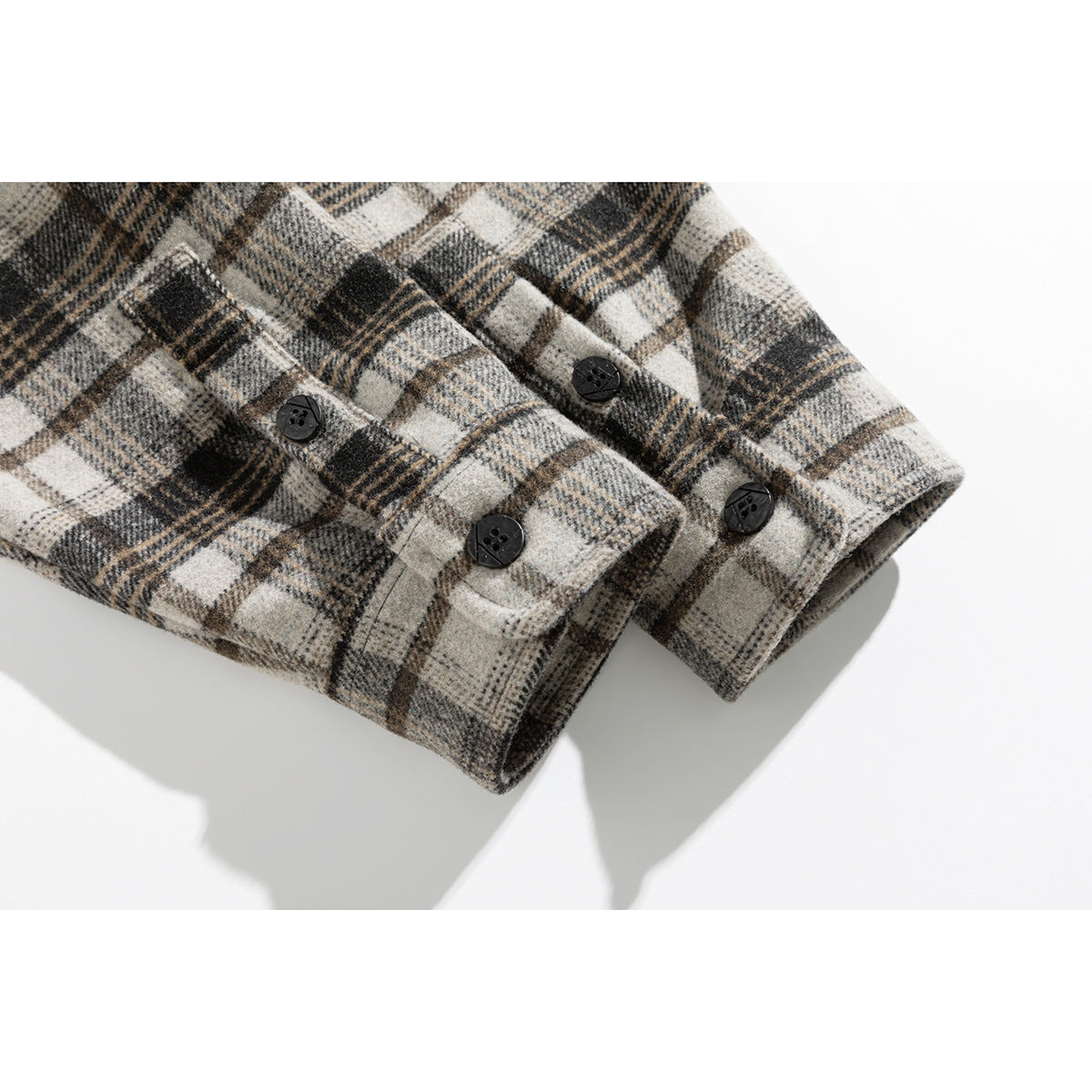 Close-up of the plaid shirt's buttoned cuffs in cream, gray, and brown.