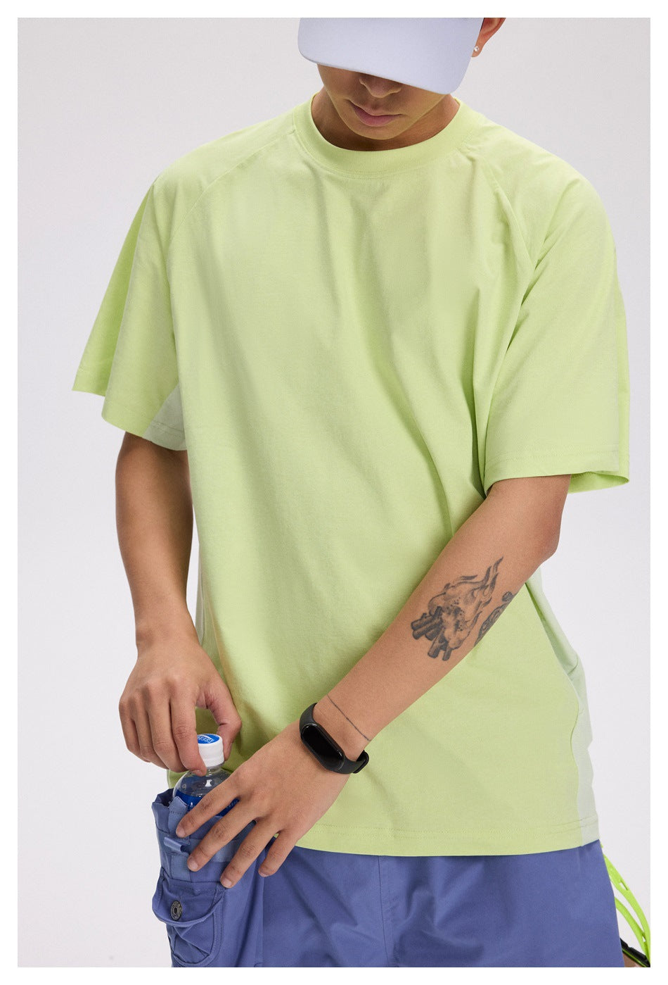 Close view of a model wearing a pale lime short-sleeve T-shirt with raglan-style sleeves and a crew neck.