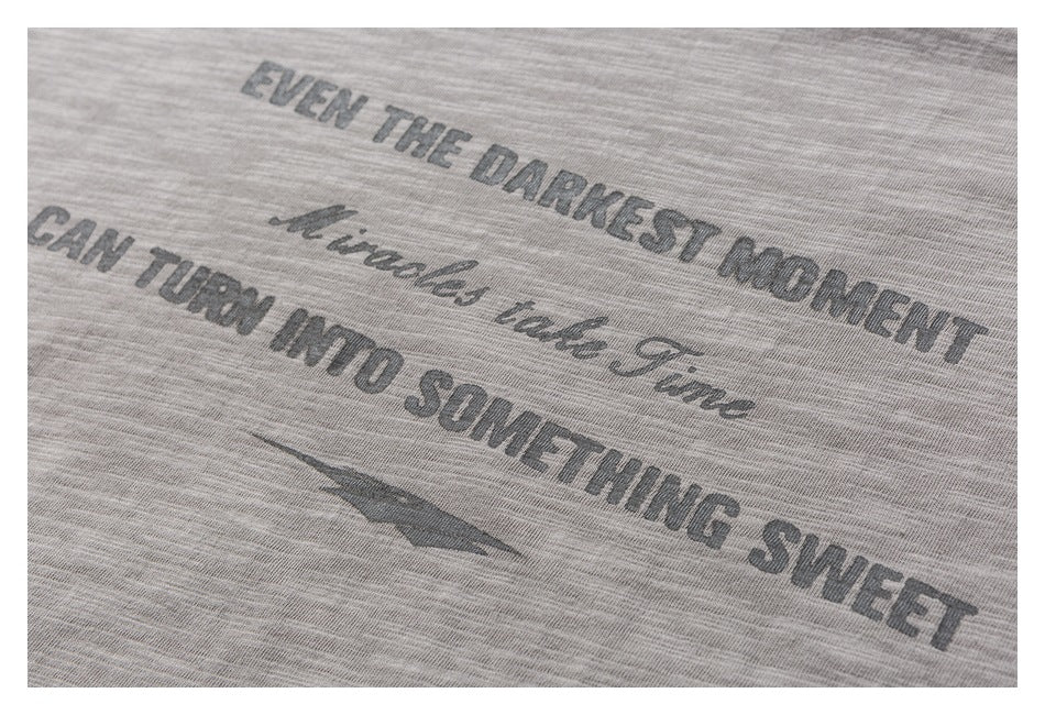 Close-up of dark English lettering and a small graphic printed on a gray marled T-shirt.