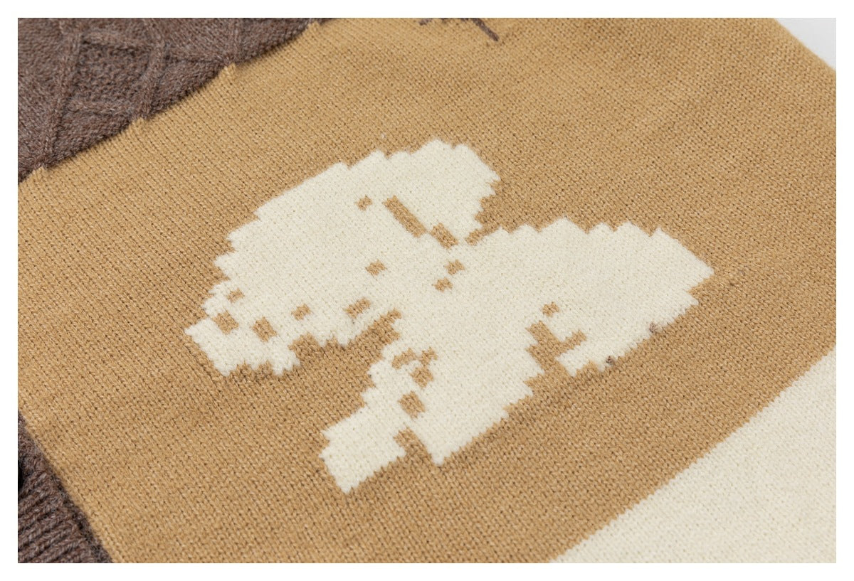 Close-up of a cream animal-shaped knit motif on a camel-colored cardigan panel.
