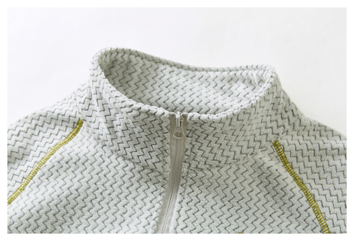 Close-up of a cream and gray zigzag-patterned top with a stand collar, short front zipper, and mustard seam accents.