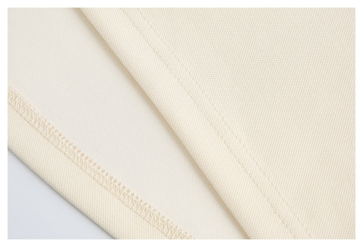 Close-up of cream garment fabric showing stitched seams and an overlocked edge.