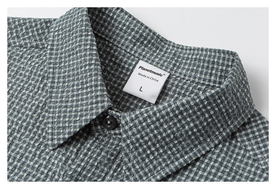 Close-up of a gray check shirt collar, dark button, and sewn-in size label.