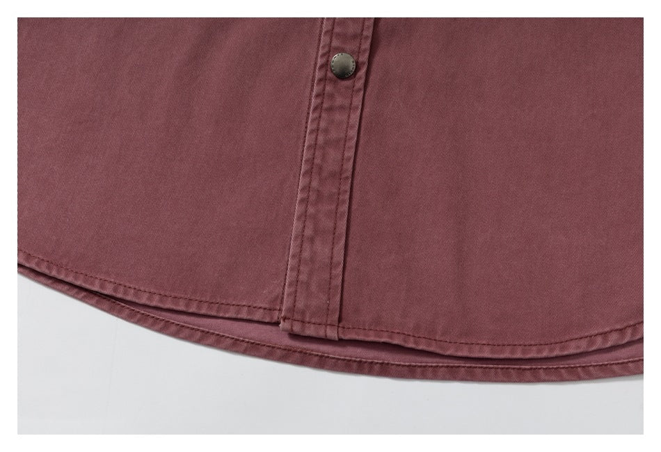 Close-up of a dusty rose garment hem with double stitching and a metal snap button.