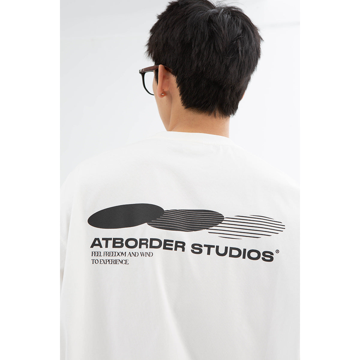 Close rear view of a white T-shirt with a large black graphic and English lettering across the back.