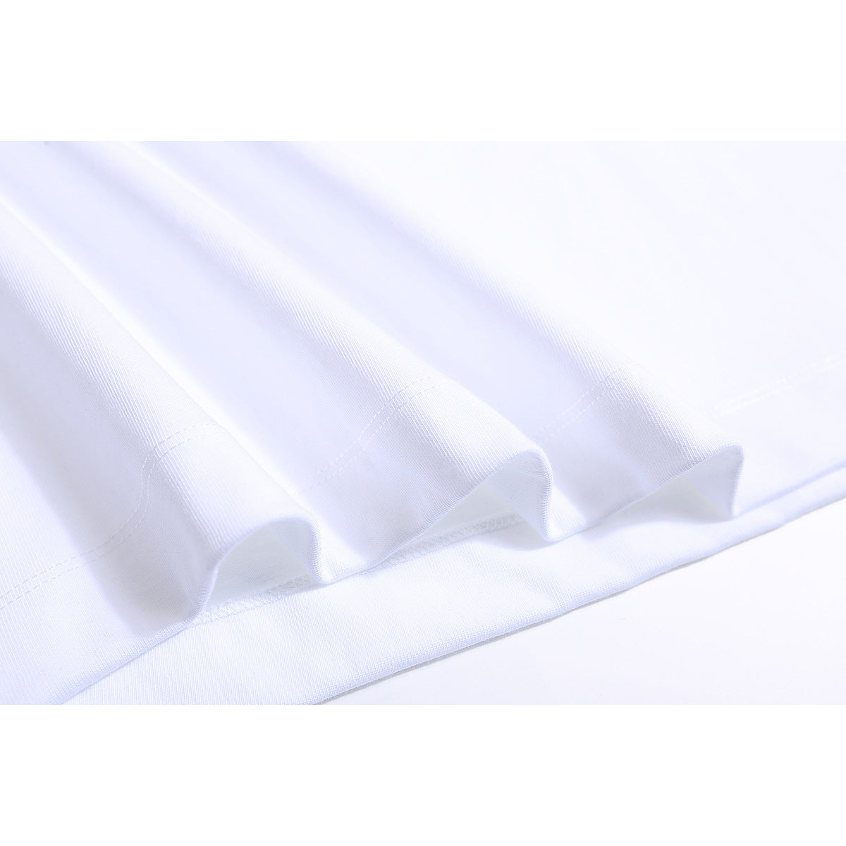 Close-up of the white T-shirt’s folded hem and stitching.