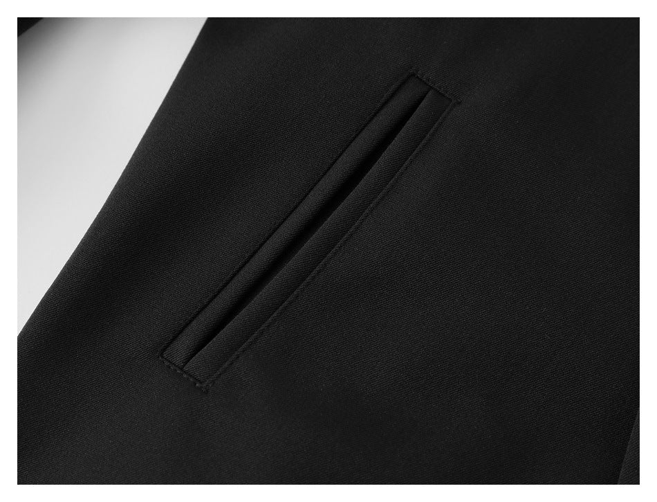 Close-up of a narrow welt pocket on black jacket fabric.