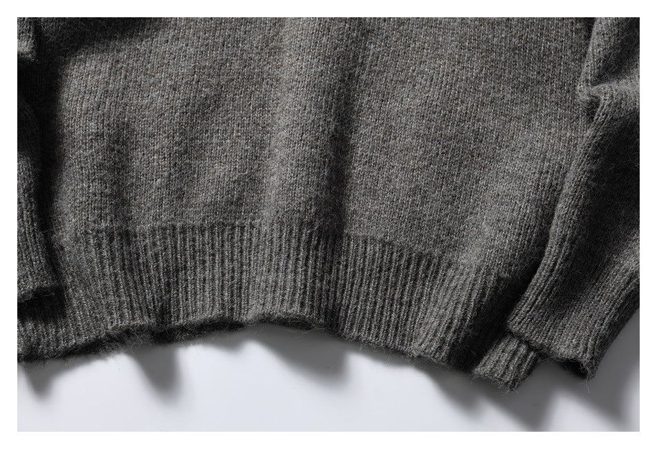 Close-up of a charcoal gray knit sweater showing its ribbed hem and sleeve cuff.