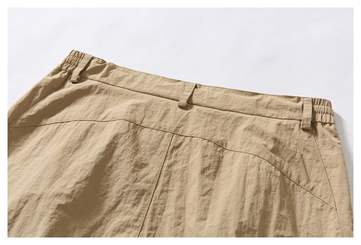 Close-up of the back waistband of beige trousers, with belt loops and curved panel seams.