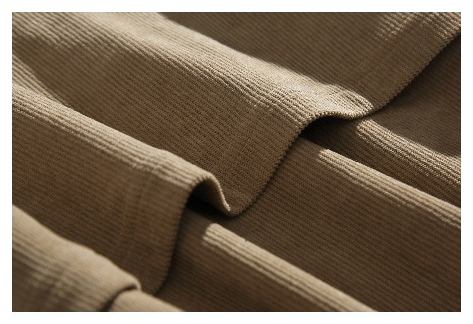 Close-up of folded tan jacket fabric showing its ribbed texture and edges.