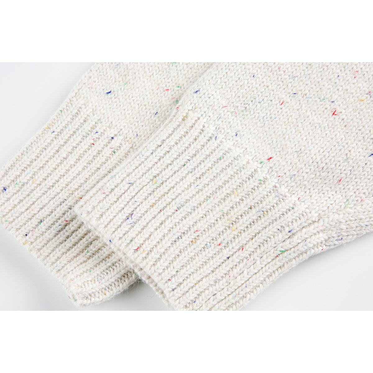 Close-up of the ribbed cream knit cuff and multicolored flecks in the fabric.