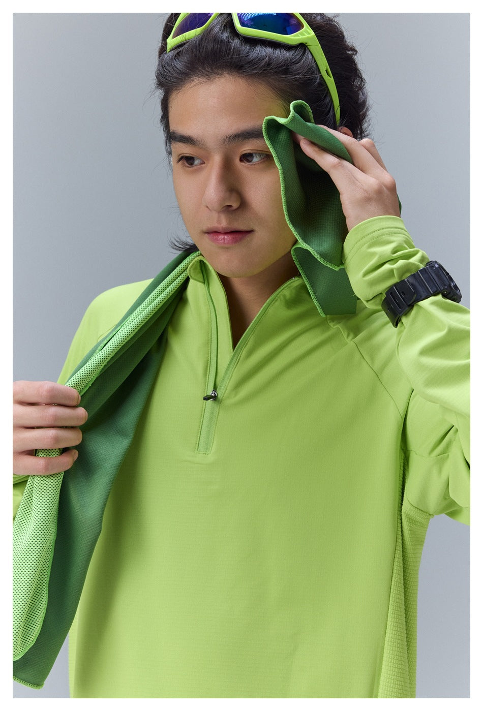 Model wearing a bright lime quarter-zip athletic top, holding a green towel.