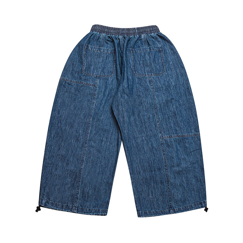 Full back view of wide-leg blue denim trousers with an elastic waist, two rear patch pockets, and adjustable hems.
