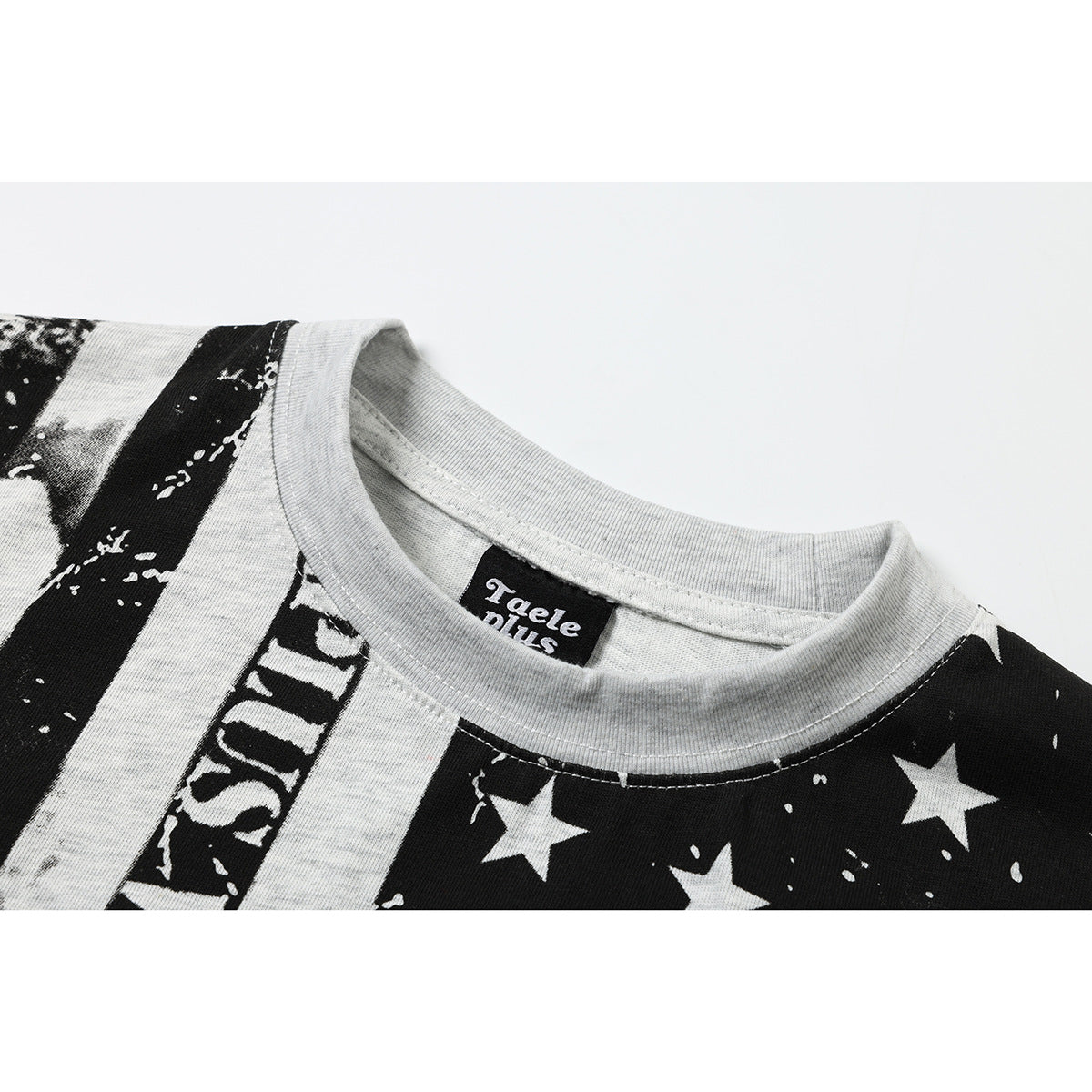 Close-up of a light gray T-shirt's ribbed crew neck and black woven label, with part of its black-and-white print visible.