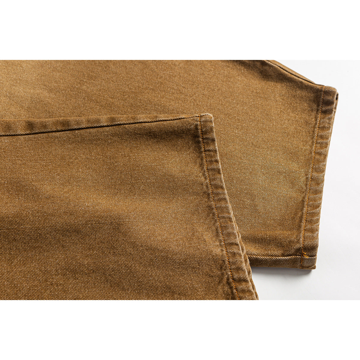 Close-up of ochre trousers showing a large rear pocket, stitching, and a cuffed hem.