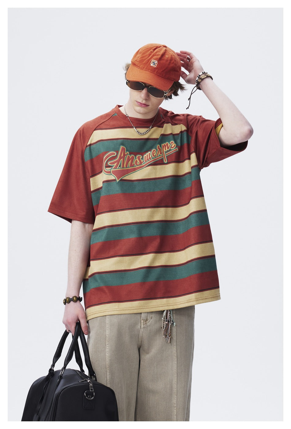 Closer front view of a model wearing a rust, teal and cream striped graphic T-shirt.