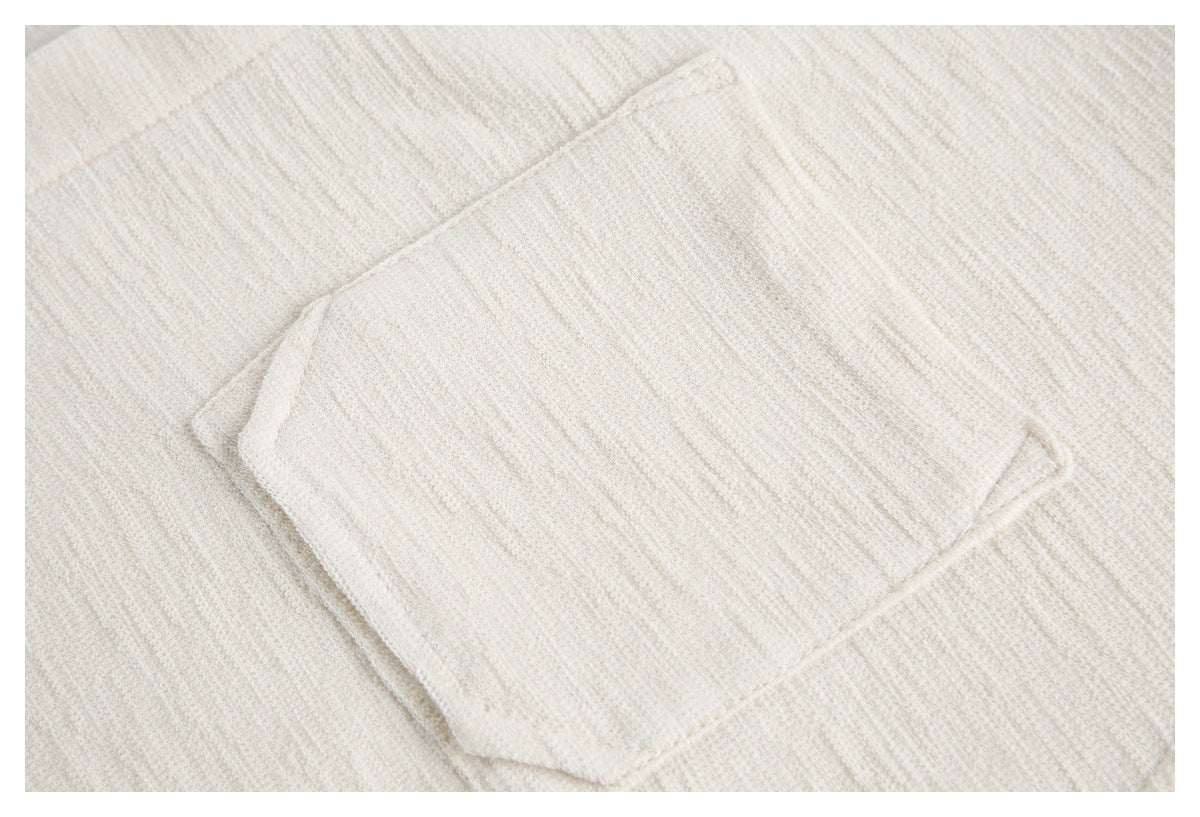 Close-up of a rectangular patch pocket on ivory textured fabric.