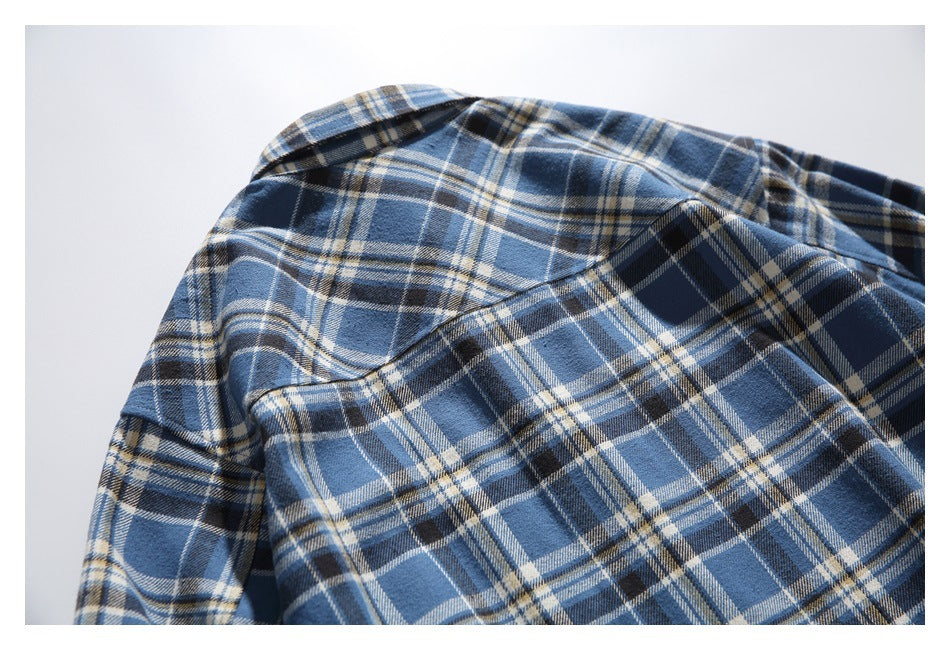 Close-up of the back shoulder and yoke of a blue plaid shirt.