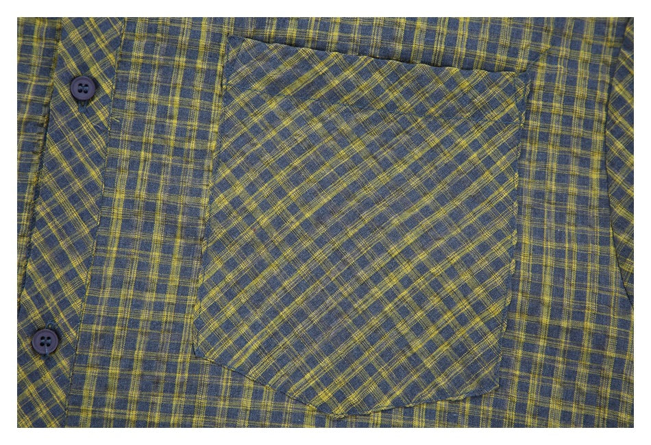Close-up of a blue-gray and mustard plaid shirt pocket and dark buttons.