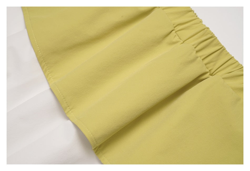 Close-up showing stitching and folds in the pale yellow-green ruffle waistband of the white pants.