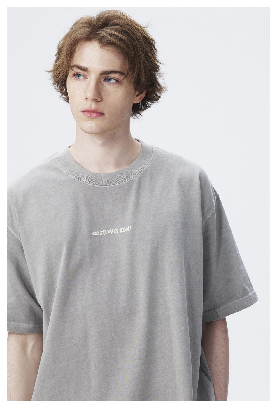 Close-up of a model wearing a light gray oversized T-shirt with small white “answer me” chest lettering.