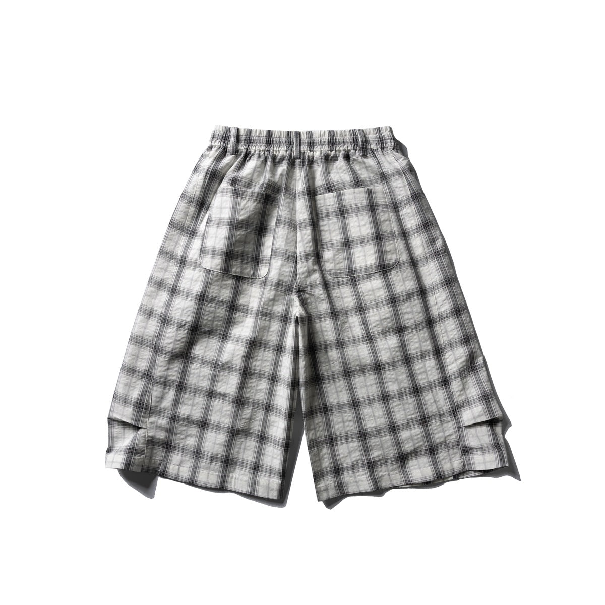 Back view of white and gray plaid wide-leg shorts with two patch pockets, elastic waistband and hem slit detail