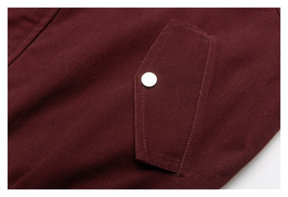 Close-up of a burgundy garment pocket with a round silver snap button.