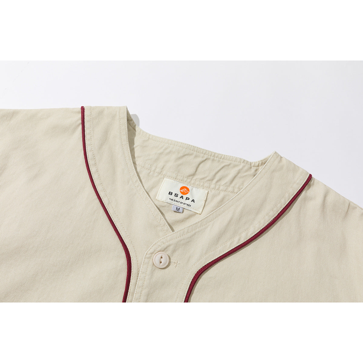 Close-up of a cream shirt collar with burgundy piping, a button, and a visible neck label.