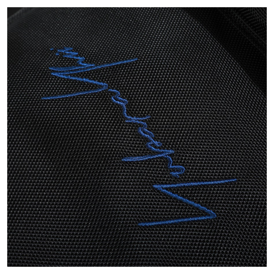 Close-up of blue embroidery on the textured black fabric of a backpack.